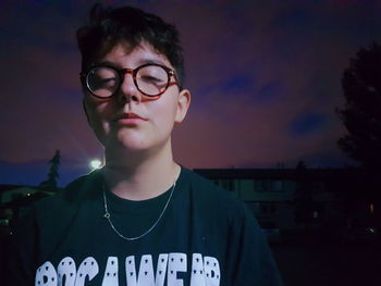 Portrait of young man with eyeglasses standing at night