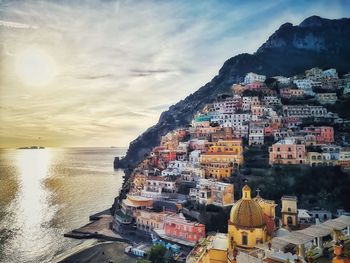 Panoramic view of sea and buildings against sky during sunset