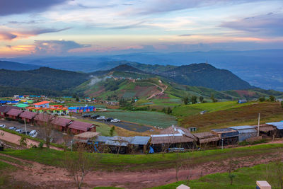 Scenic view of agricultural field by buildings against sky