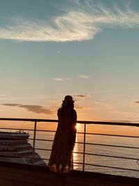 Silhouette man looking at sea against sky during sunset