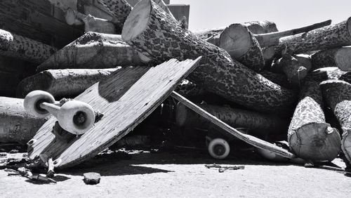 Broken skateboard among a pile of logs