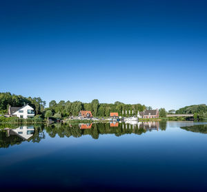 Reflection of building in lake against clear blue sky