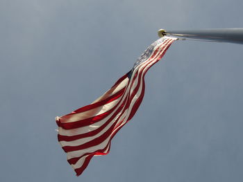 Low angle view of red flag against blue sky