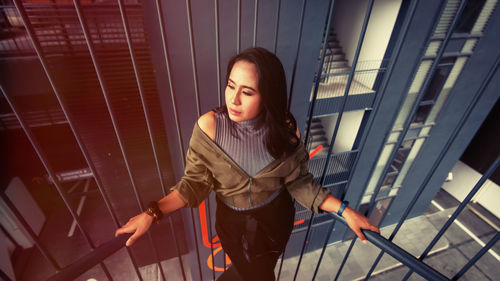 Young woman looking away while standing on railing