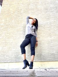 Full length portrait of woman standing against wall