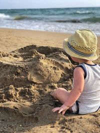 Midsection of woman sitting on sand at beach