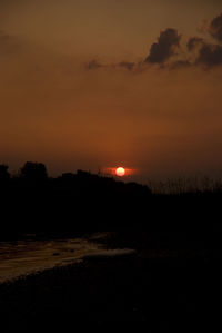 Scenic view of silhouette field against orange sky