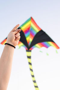 Midsection of person holding multi colored flag against clear sky