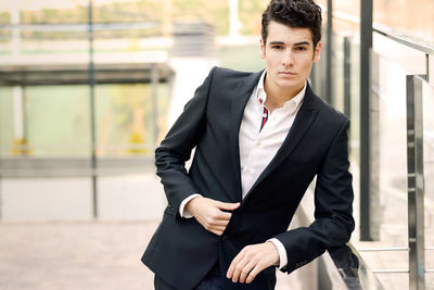 Portrait of young man in suit leaning on railing