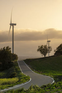 Road in agricultural fields with wind turbines generating clean electricity in catalonia spain