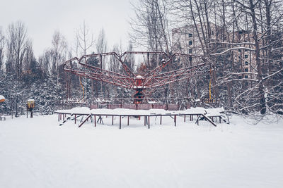 Bare trees on snow covered land against sky