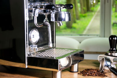 Coffee maker by roasted beans on table