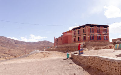 Built structure on land by mountain against sky