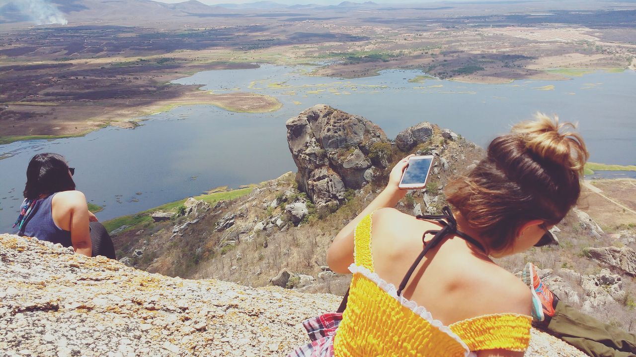 rear view, real people, leisure activity, lifestyles, day, two people, outdoors, standing, casual clothing, togetherness, women, nature, water, mountain, beauty in nature, young adult, young women, sky