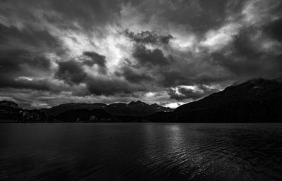 Scenic view of lake and mountains against cloudy sky