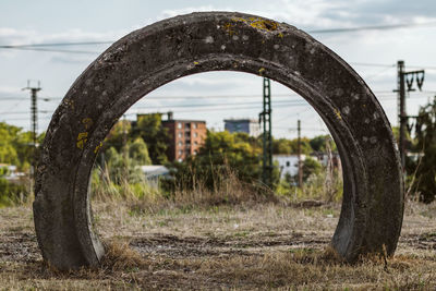 Close-up of old rusty wheel on field against sky