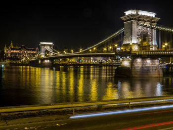 Illuminated bridge over river at night