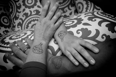 Cropped hands of family with tattoos on bed