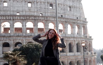 Portrait of woman standing against historic building
