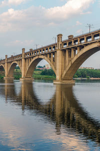 Arch bridge over river against sky