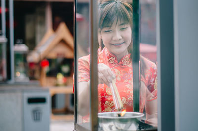 Smiling young woman burning incense