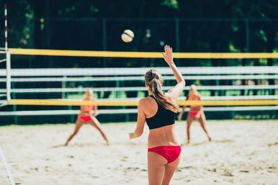 Rear view of woman playing beach volleyball