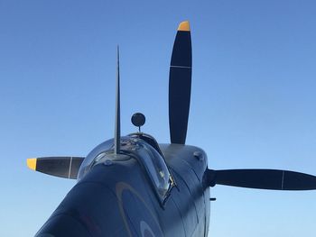 Low angle view of airplane flying against clear blue sky