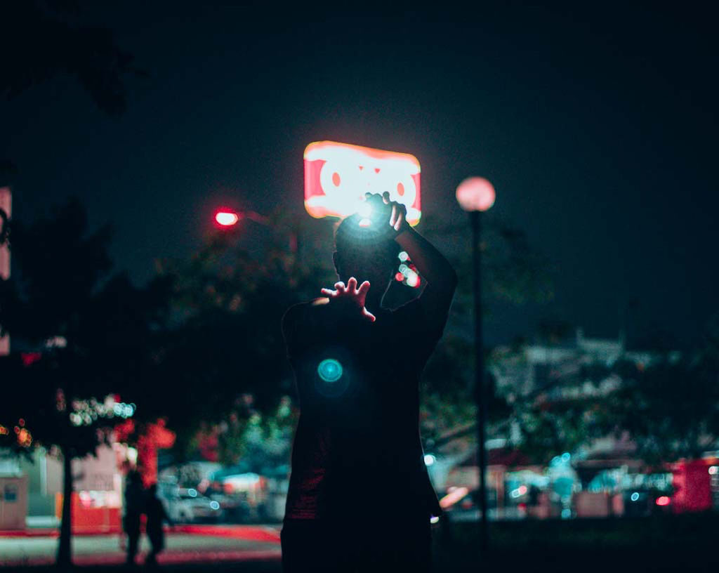 PERSON HOLDING ILLUMINATED LIGHTING EQUIPMENT ON STREET IN CITY