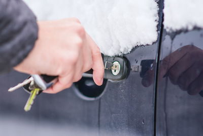 Cropped hand of man opening car door during winter