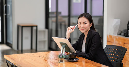 Young woman sitting on table at home