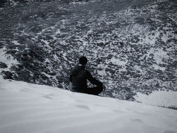 Rear view of man on snowcapped mountain during winter