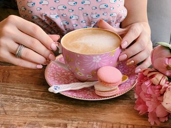 Midsection of woman holding coffee cup on table