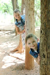 Portrait of happy siblings on tree trunk