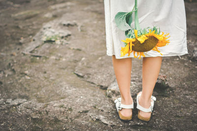 Low section of woman with yellow flower