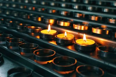 Three burning candles in between many candles at church