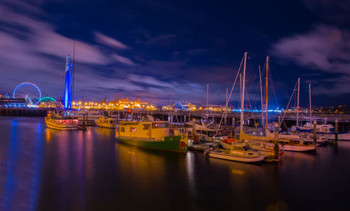 Sailboats moored at harbor against sky at night