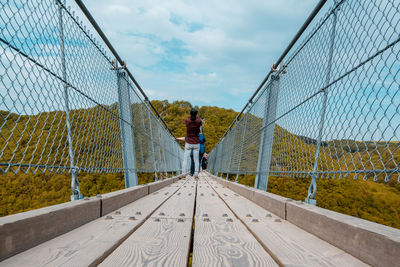 Rear view of man standing on bridge