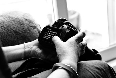 Midsection of person holding camera at home