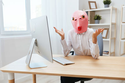 Rear view of woman using laptop at desk in office