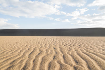 Scenic view of sand dunes against sky