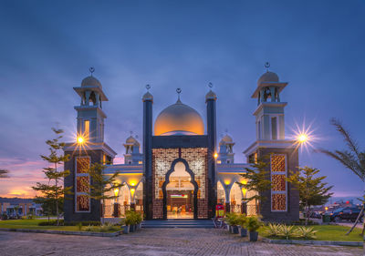 Illuminated entrance of historic building against sky at night