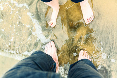 Two pairs of feet in the sand of the sea . four legs on the sea water . romantic rendezvous 
