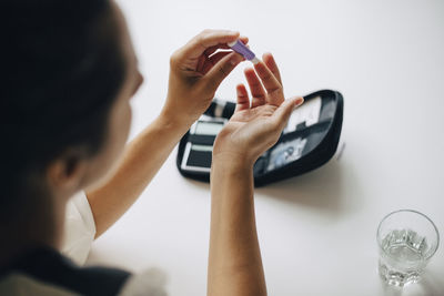 High angle view of woman doing blood sugar test at table