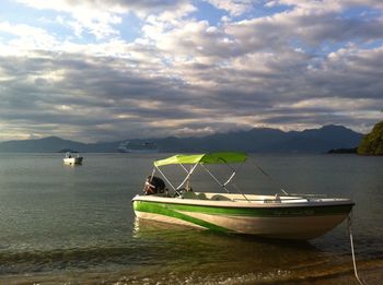 Boats sailing in sea against cloudy sky