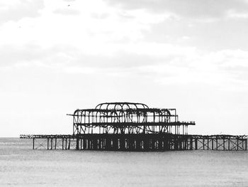 Pier on sea against cloudy sky