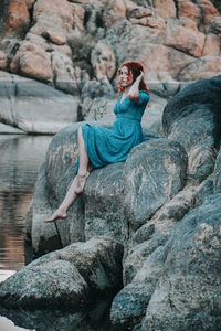 Full length of young woman sitting on rock