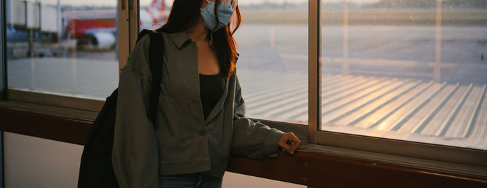 Midsection of woman standing by train window