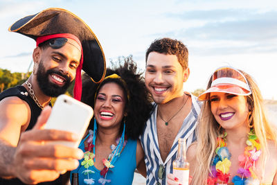 Cheerful friends doing selfie against sky