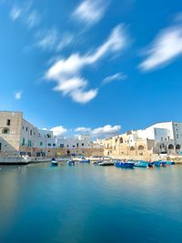 Buildings by river against sky
