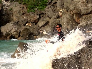 Man standing on rock by sea